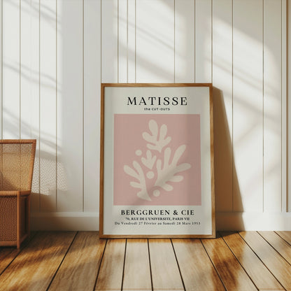 Matisse Cut-Outs Berggruen & Cie Paris VII poster in a wooden frame, styled in a bright room with wooden flooring and wicker furniture.