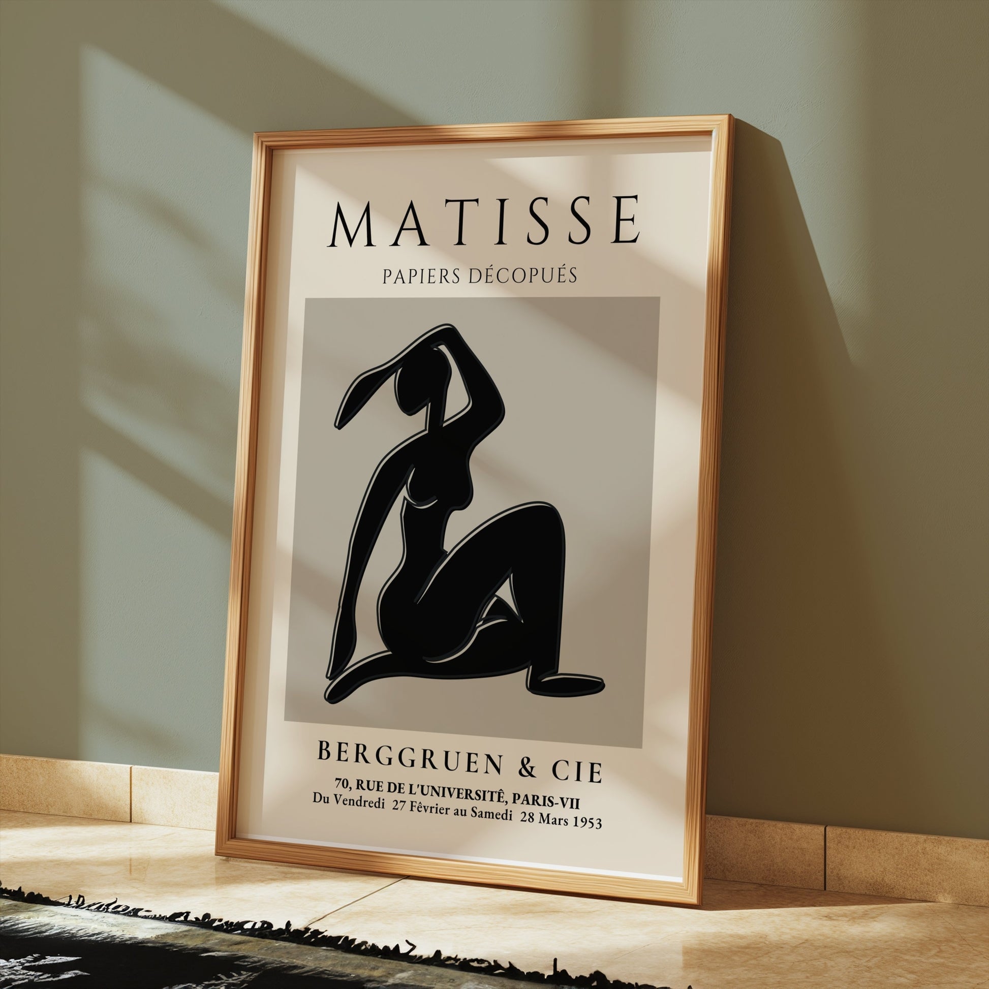 Matisse Exhibition Papiers Decoupés Berggruen Poster leaning against a green wall, framed in light wood for modern art lovers.