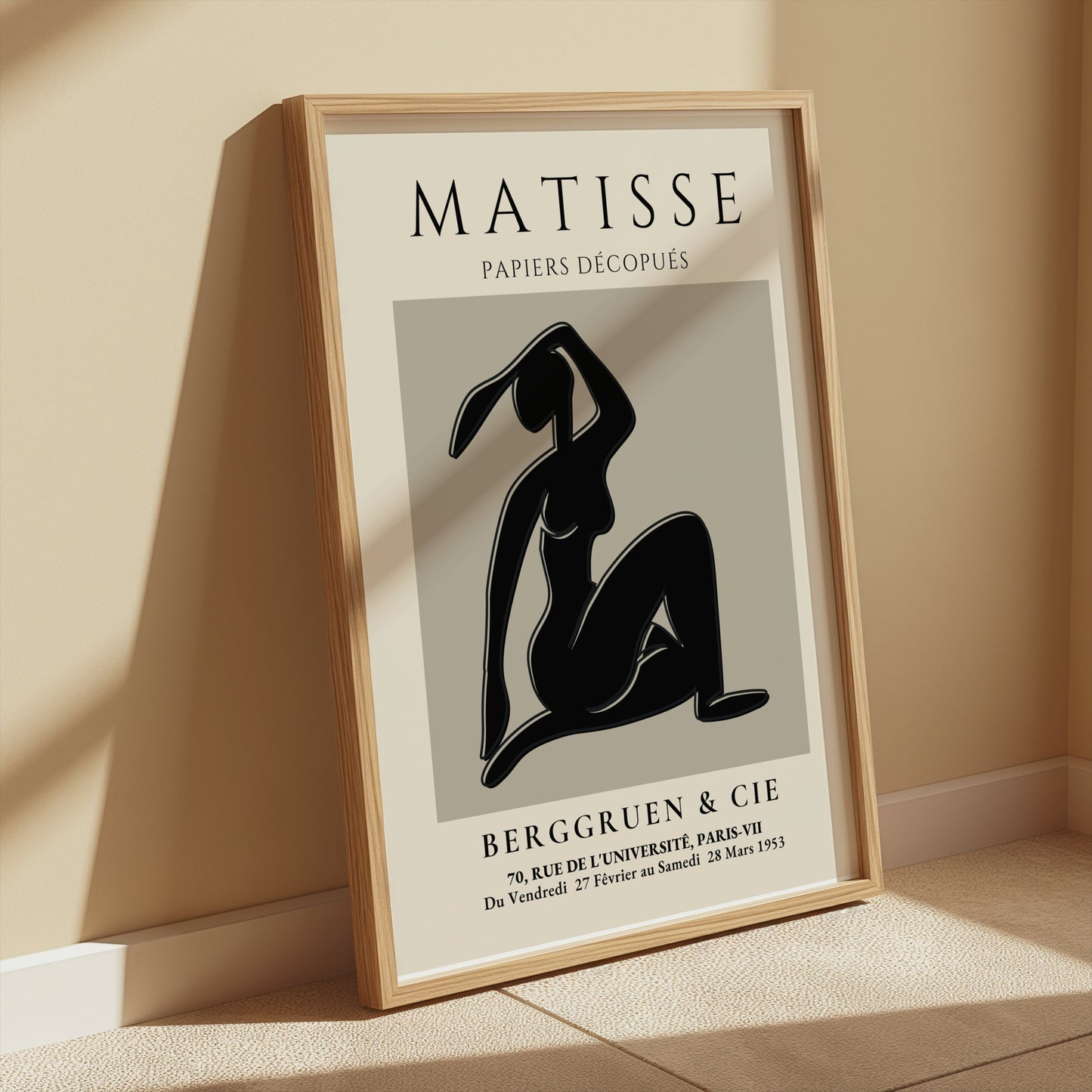 Matisse Exhibition Papiers Decoupés Berggruen Poster leaning on a beige wall, framed in wood, ideal for modern and vintage decor.