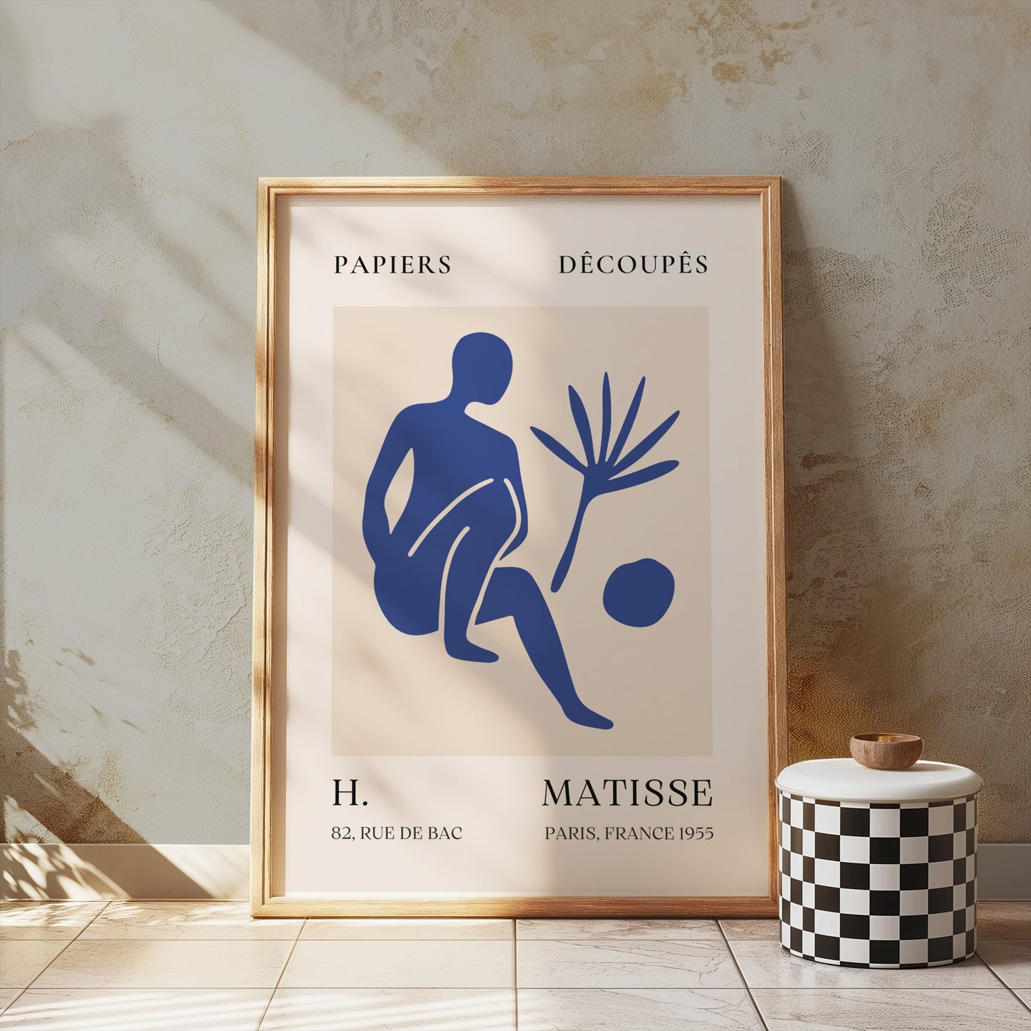 Matisse inspired art poster in a wooden frame, featuring a blue abstract figure, displayed against a textured wall with soft lighting.