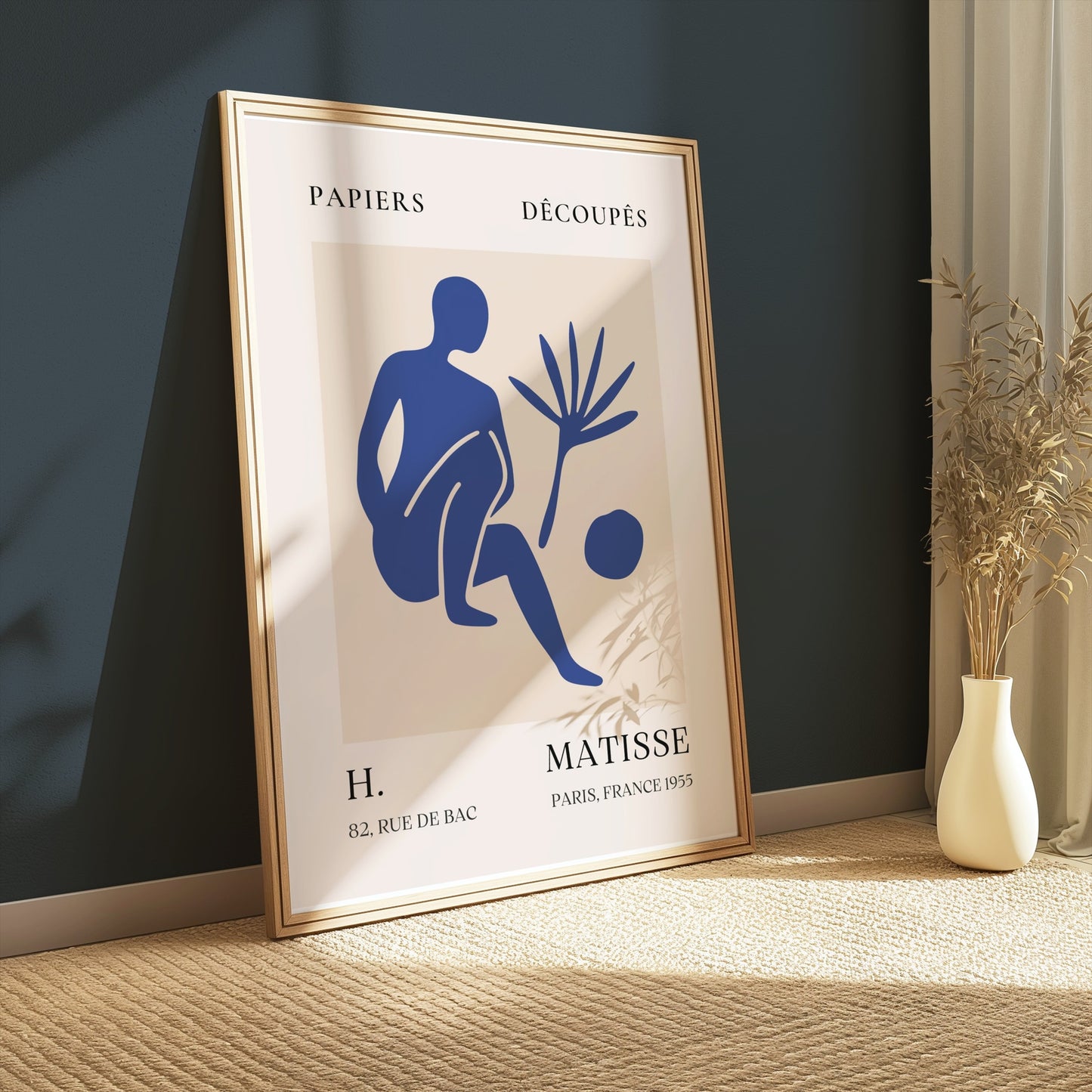 Framed Matisse inspired art poster with a blue abstract figure, leaning against a dark green wall, styled with a vase and natural light.