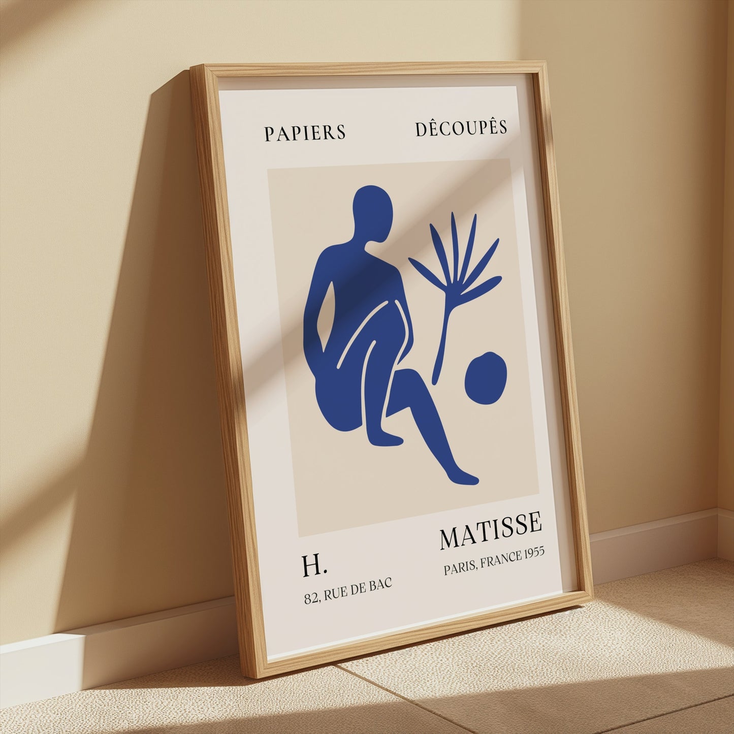 Framed Matisse inspired modern art poster featuring a blue abstract figure, leaning against a beige wall with warm sunlight streaming in.