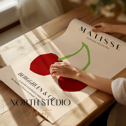 Unframed Matisse Papiers Découpés cherry art print poster being unrolled on a wooden table, showcasing its vibrant minimalist design.