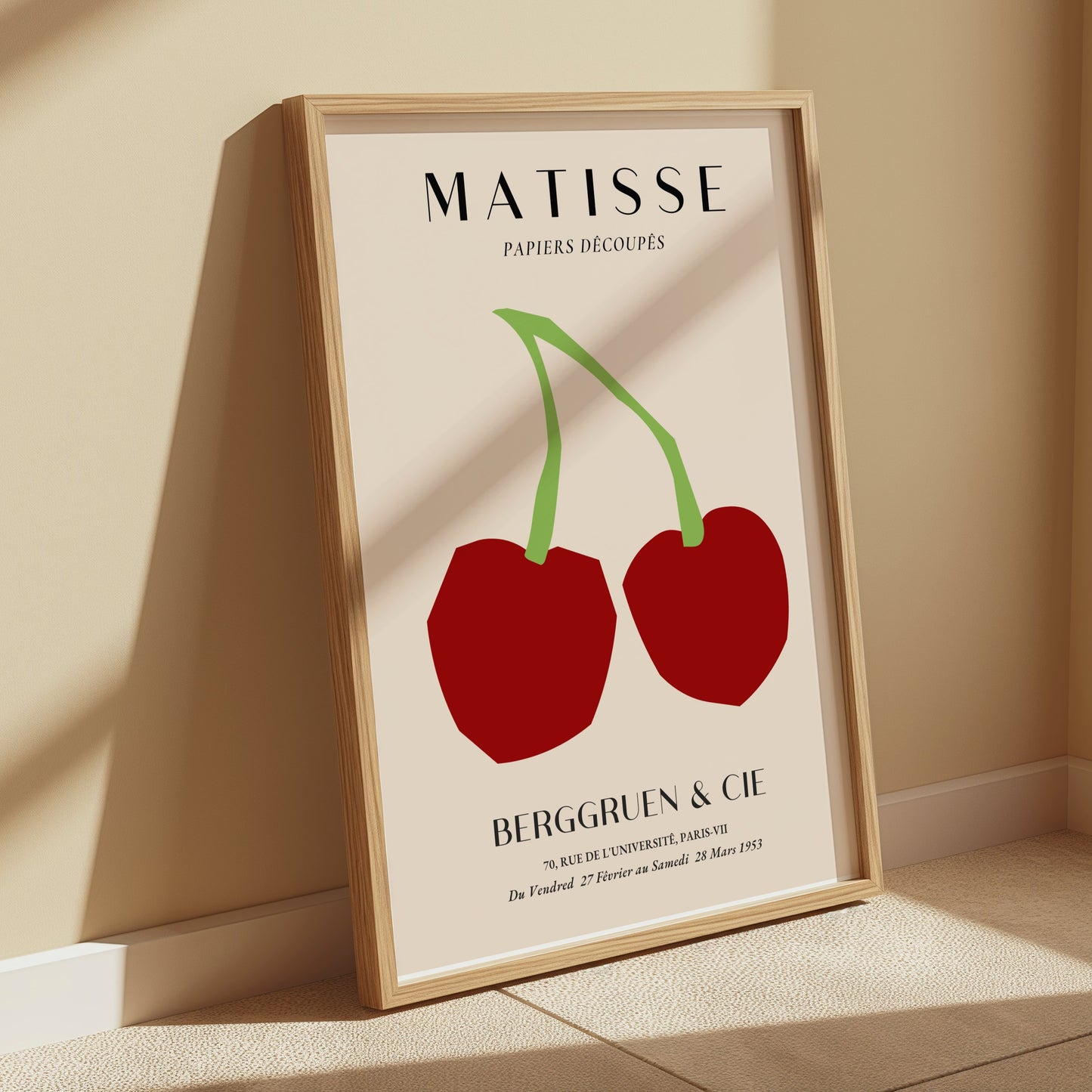 Framed Matisse Papiers Découpés art print poster with red cherry design, displayed leaning against a beige wall in natural sunlight.