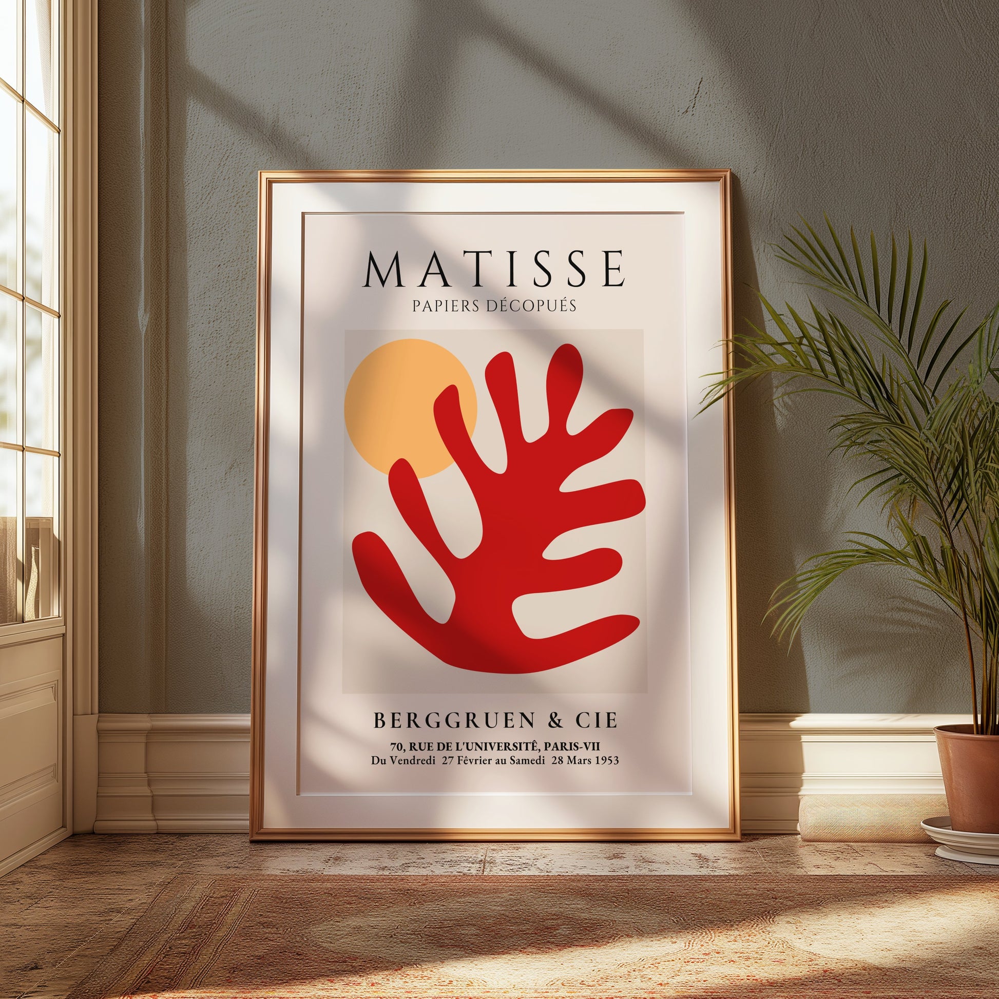 Large framed Matisse Art Poster featuring red coral and orange sun, leaning against a wall in a bright room with natural light and greenery.