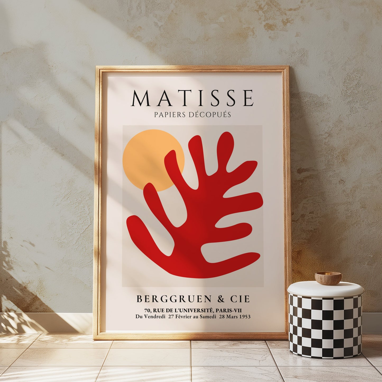 Framed Matisse Art Poster with red coral cut-out and orange sun, styled in a minimalist room with a checkered stool and textured walls.