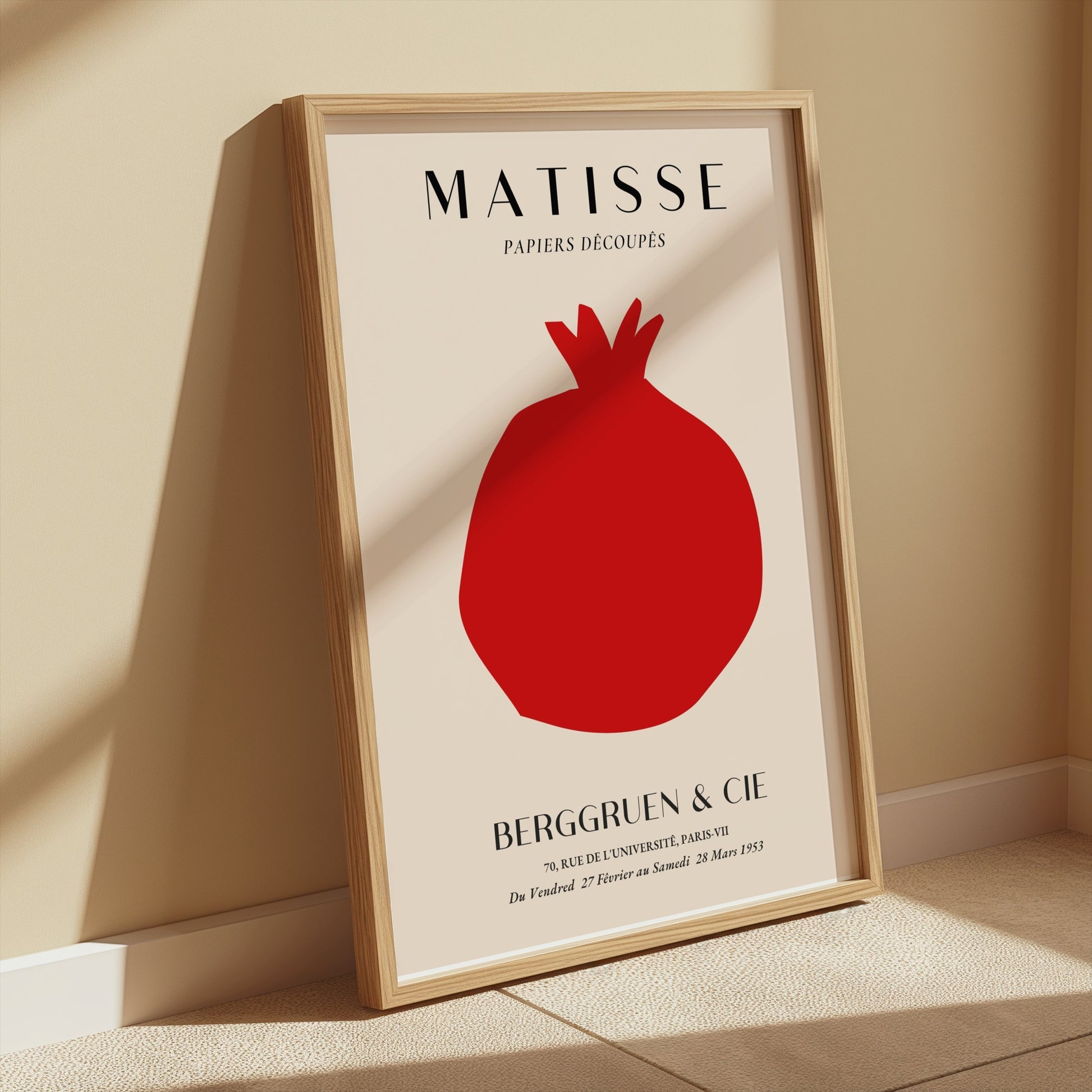 Matisse Papiers Decoupes Berggruen & Cie poster in a wooden frame leaning against a beige wall with soft sunlight illuminating the area.