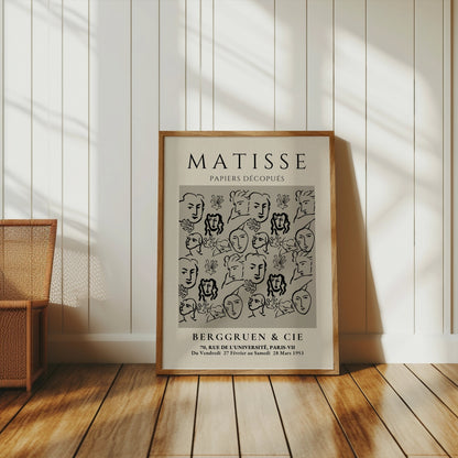 Matisse Papiers Découpés exhibition poster leaning against a white paneled wall, styled with a wicker basket for a cozy decor vibe.
