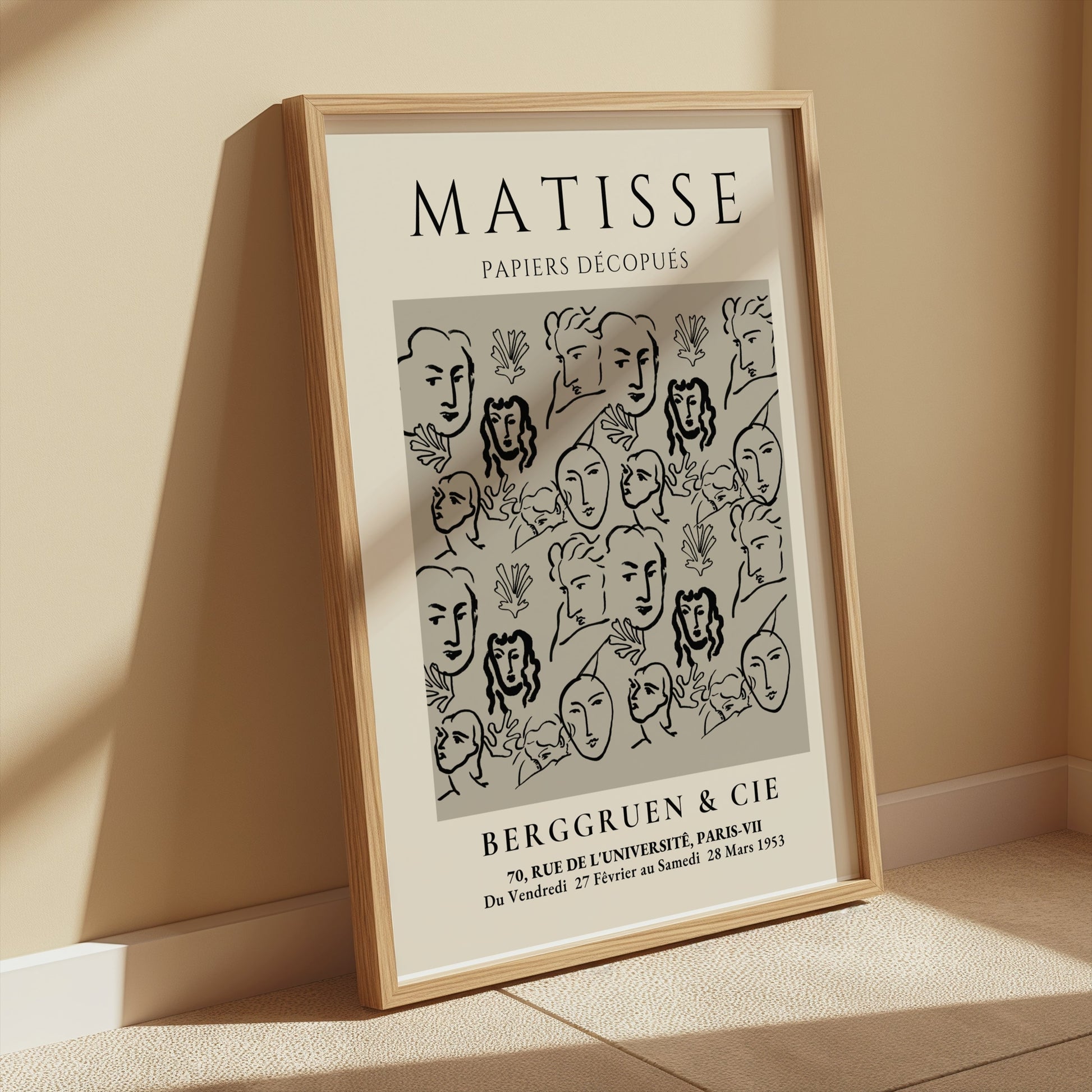 Framed Matisse Papiers Découpés exhibition poster leaning on a beige wall, bathed in warm sunlight, perfect for vintage-inspired decor.