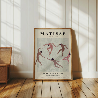Matisse The Dance exhibition poster leaning against a white paneled wall, styled with a wicker basket and natural wood flooring.