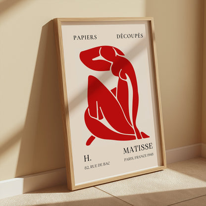 Framed Henri Matisse 'Papiers Découpés' poster with red abstract figure art, styled against a beige wall for modern home decor.
