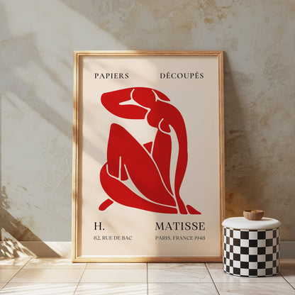 Henri Matisse 'Papiers Découpés' poster in a wooden frame, leaning against a textured wall, showcasing red abstract art for home decor.