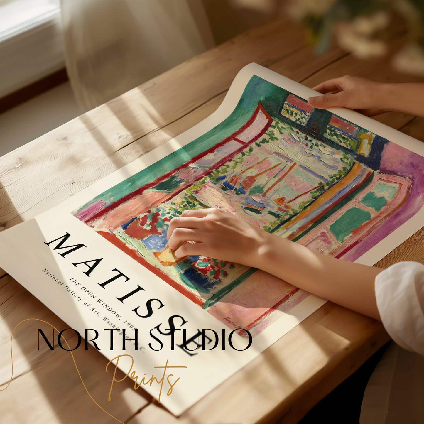Hands unrolling The Open Window by Matisse 1905 art print poster on a wooden table, showcasing its premium quality and vibrant design.