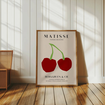Vintage Henri Matisse cherry art print in a wooden frame, leaning against a white paneled wall with natural sunlight streaming in.