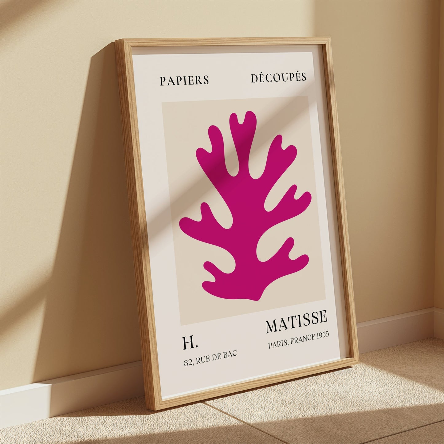 Vintage Papiers Découpés poster by H Matisse, France 1955, framed and leaning against a beige wall with soft sunlight highlighting the artwork.