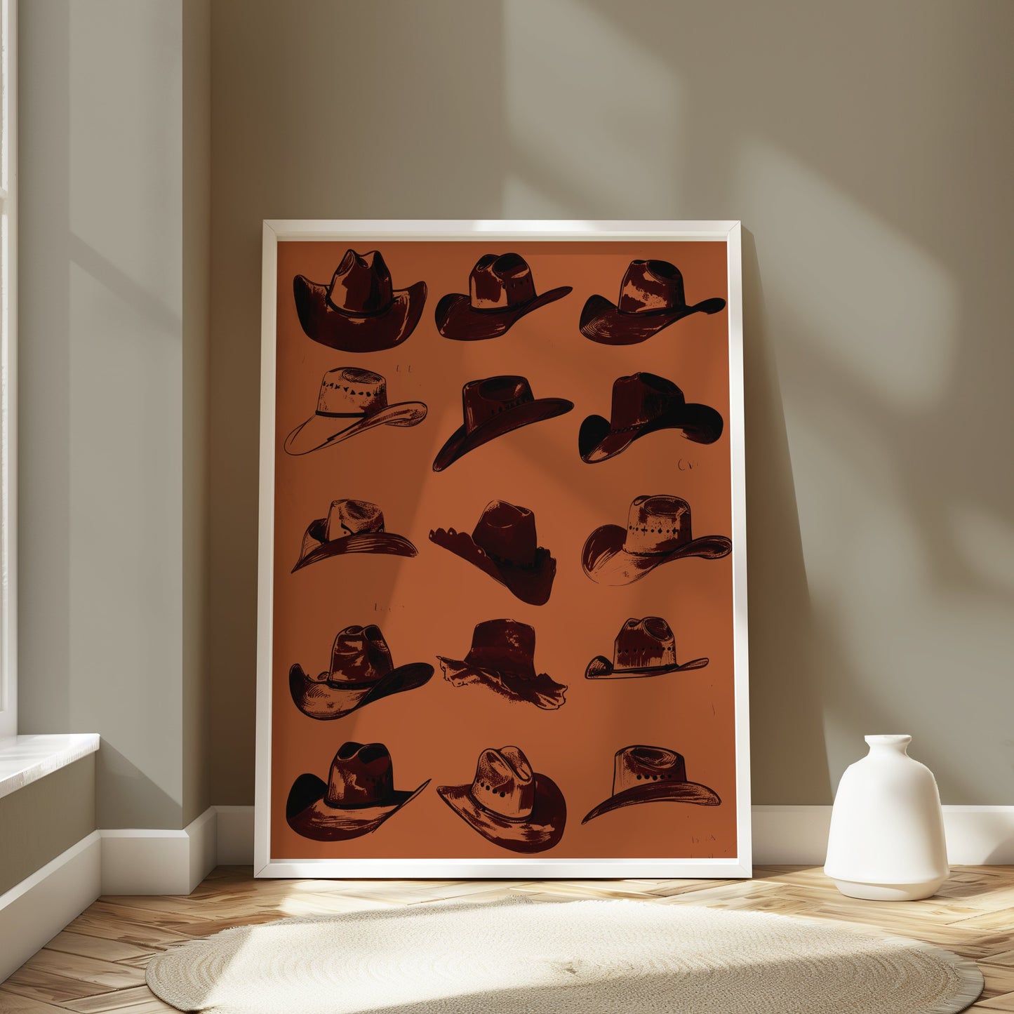 Cowboy hats art poster in a white frame leaning against a wall in a bright room, styled with modern and rustic decor elements.