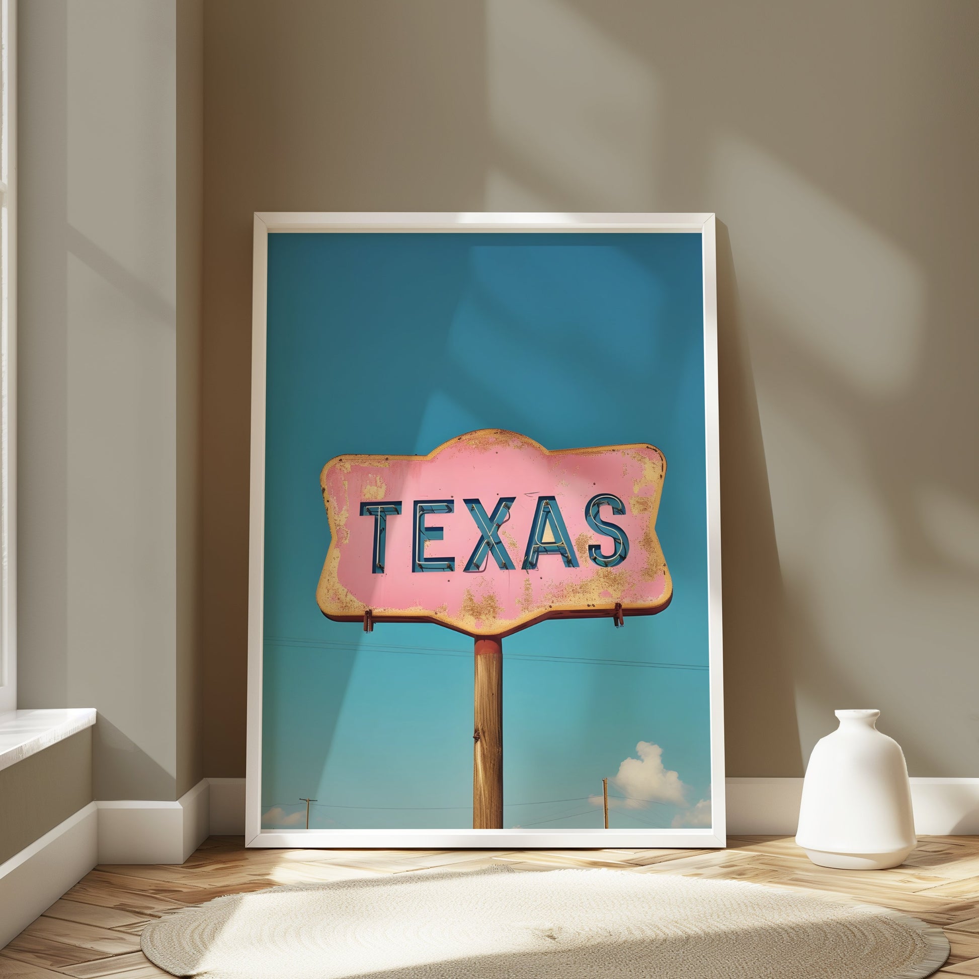Framed Texas retro sign wall art with a pink and blue design leaning against a wall in a bright, minimalist interior.