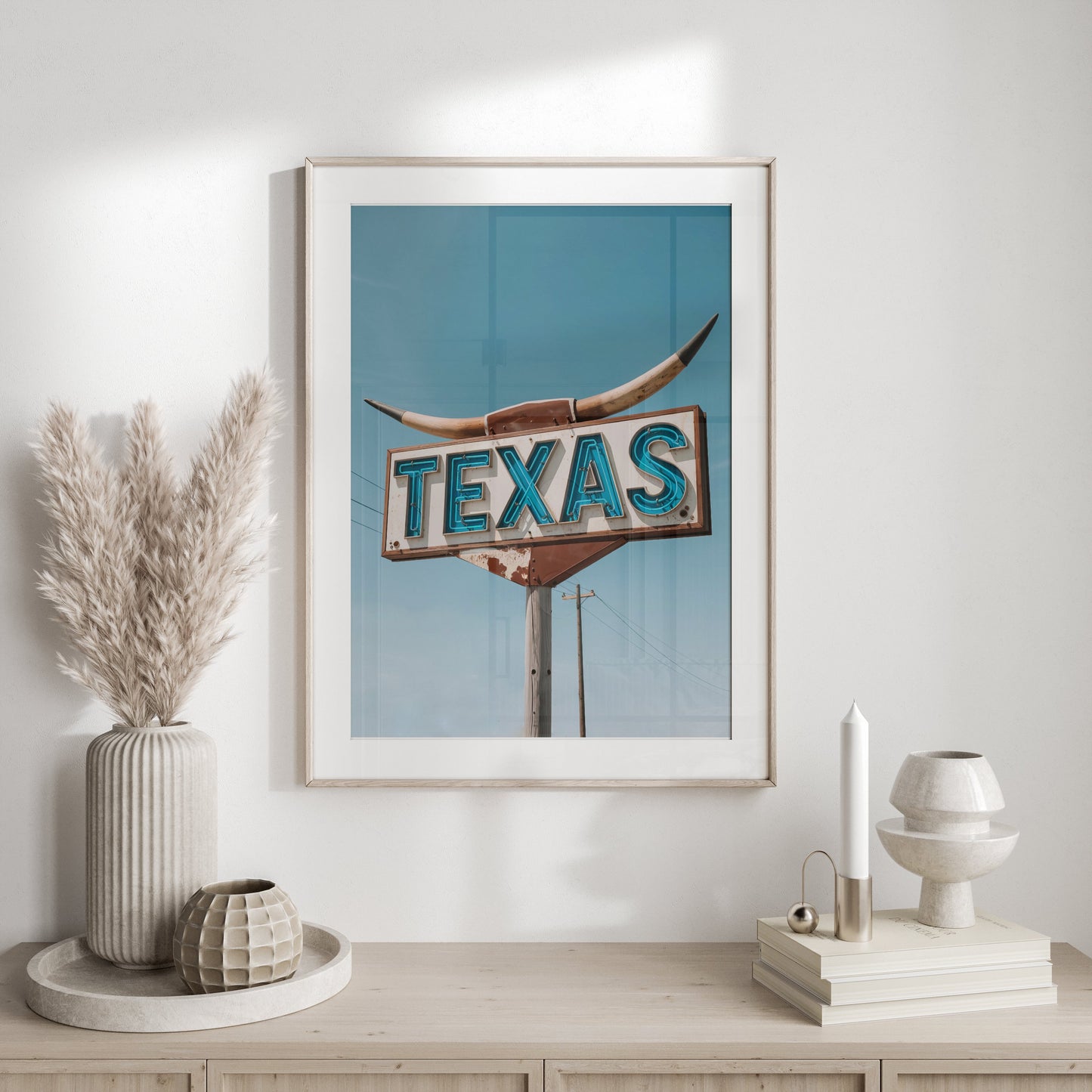 Framed Texas roadside sign art print styled on a white console table with neutral decor and pampas grass in a modern setting.