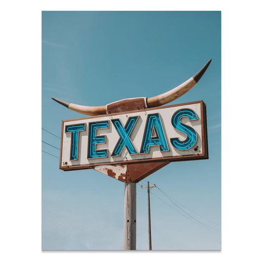 Vintage Texas roadside sign art print with a rustic design featuring bold blue lettering and a longhorn motif against a clear sky.