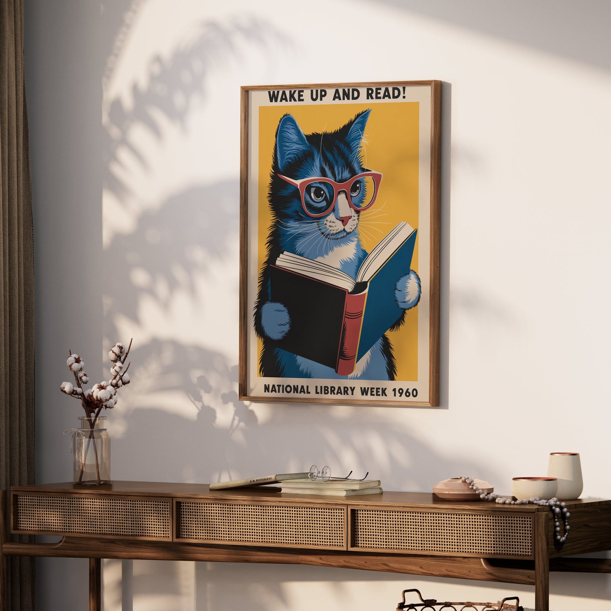 Framed cat reading poster hung on a wall above a wooden console table, styled with books and minimalistic decor for a cozy vibe.