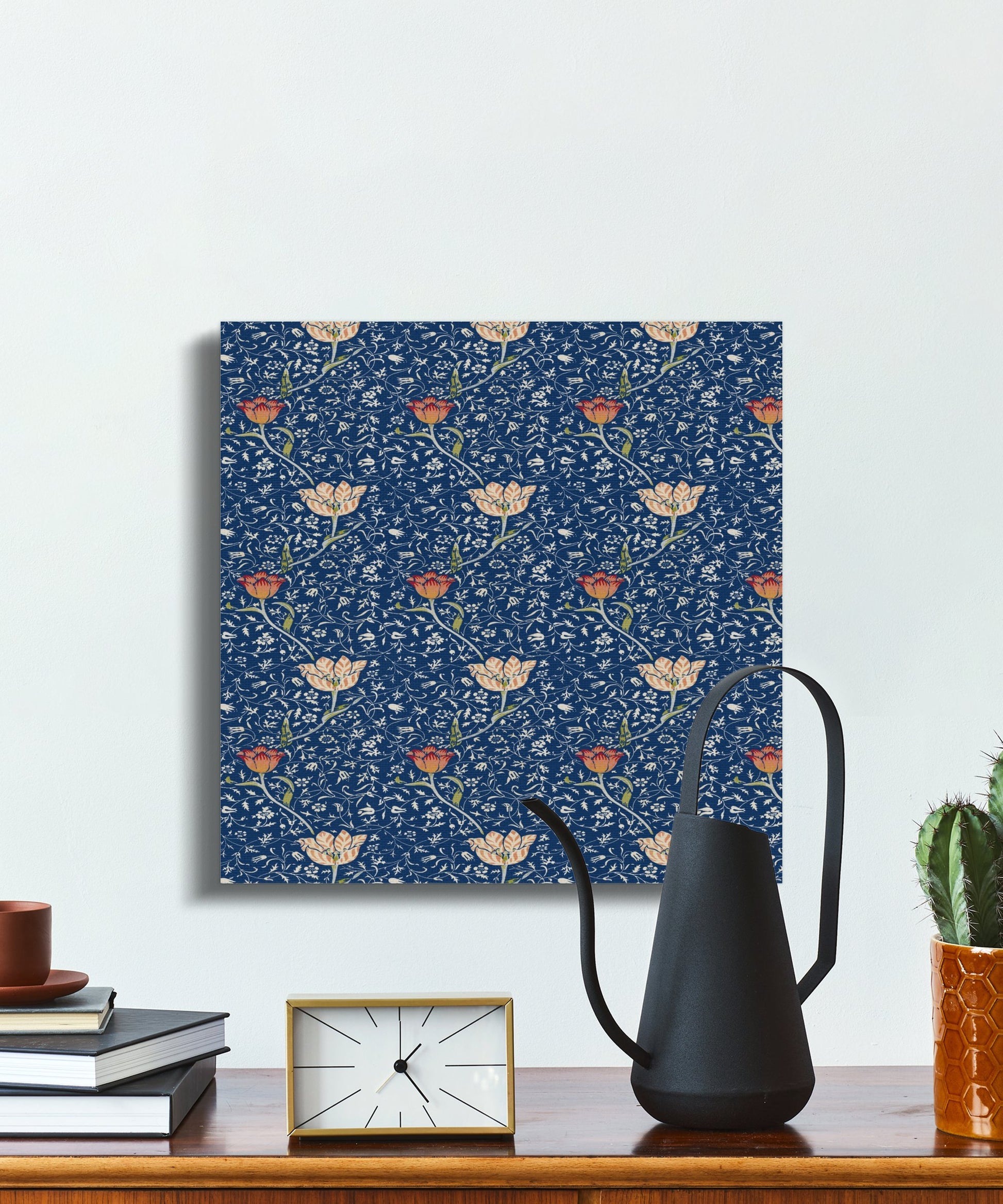 Square William Morris floral canvas wrap with intricate blue and orange botanical design, styled on a desk with books and modern decor.