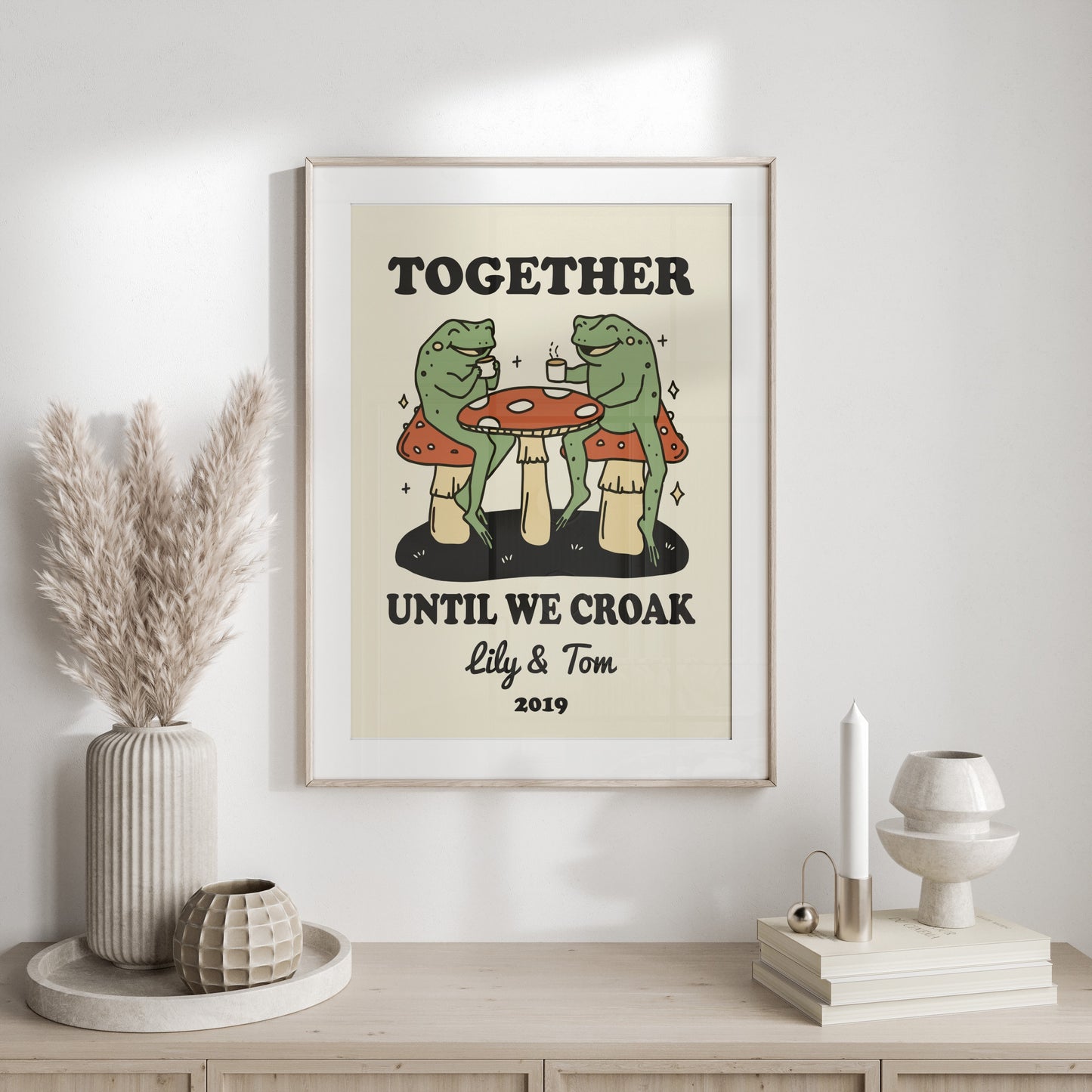 Frogs drinking coffee at a mushroom table, "Together until we croak" with names and year.