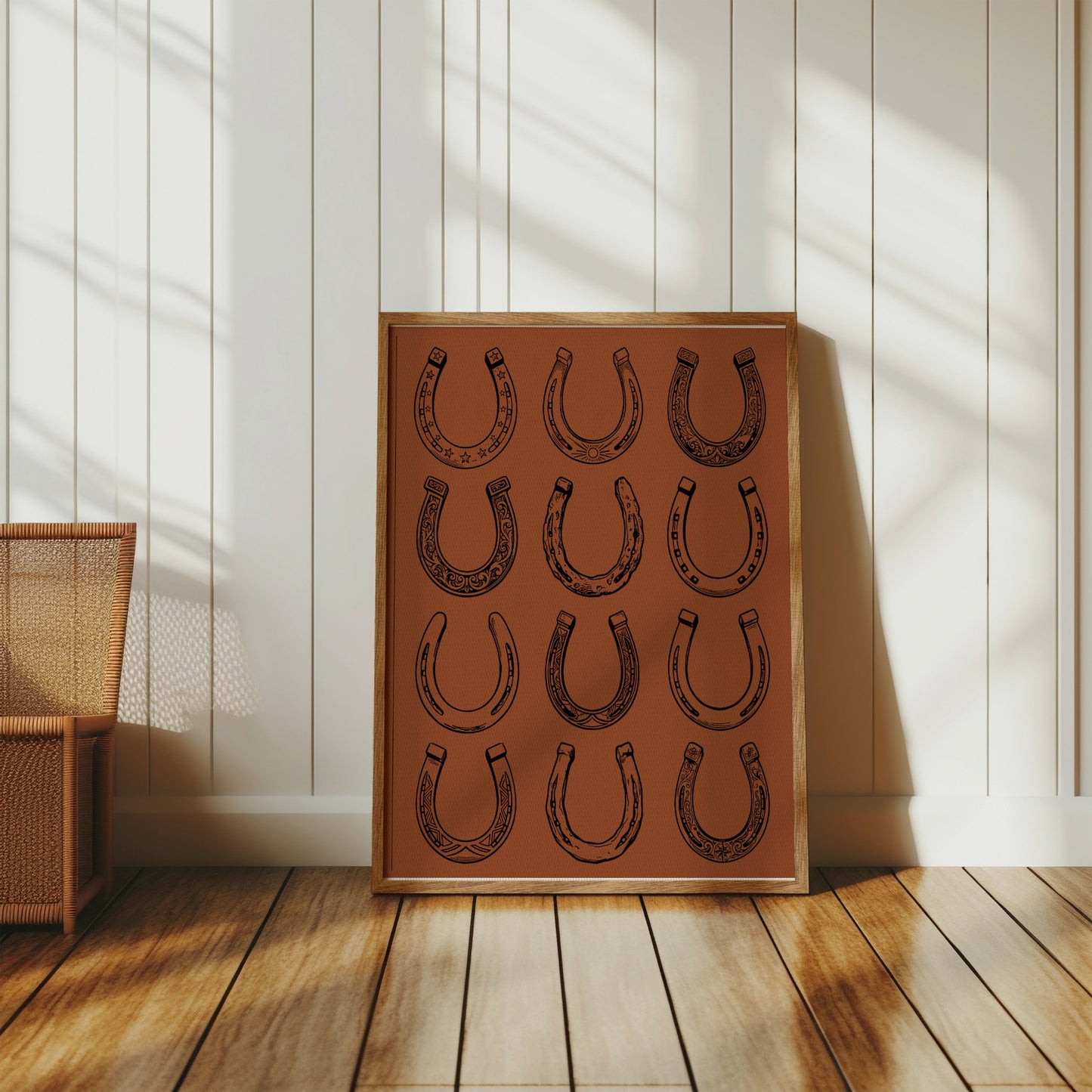 Framed artwork displaying a grid of twelve stylized horseshoes on a textured brown background.